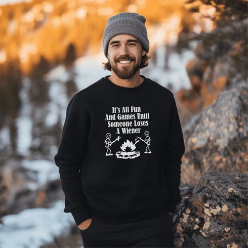 Our Camping sweatshirt features two stick people roasting wieners over a campfire with the hilarious saying, "It's All Fun & Games Until Someone Loses A Wiener."